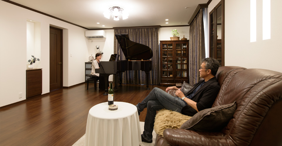 ソファでワインを飲む夫とグランドピアノを弾く妻