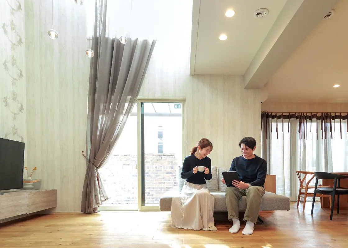 吹き抜けのあるリビングのソファに座る夫婦