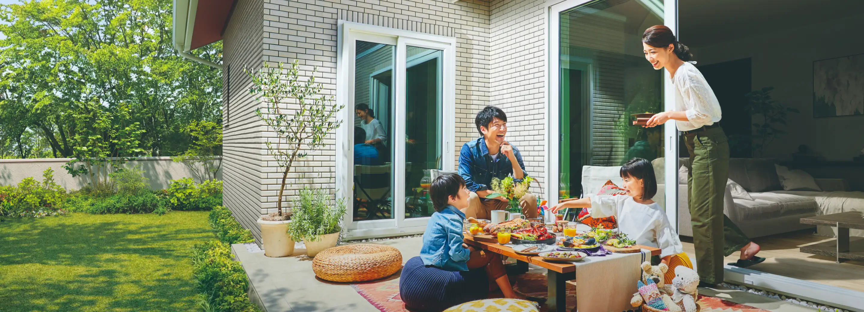 うちそとを繋ぐ平屋のテラスで家族が団らんしている様子